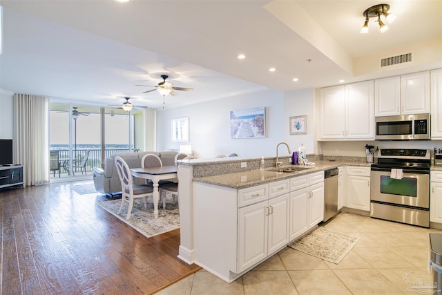 kitchen with a peninsula, a sink, visible vents, white cabinetry, and appliances with stainless steel finishes