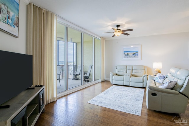 living area with expansive windows, ceiling fan, and wood finished floors