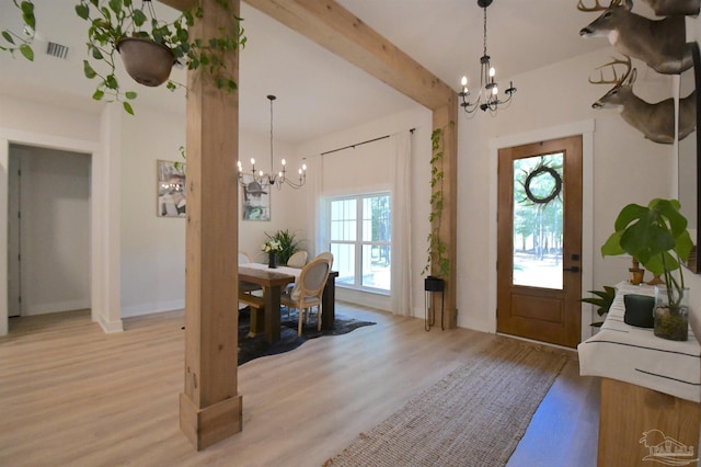 entrance foyer featuring beam ceiling, light wood-type flooring, and an inviting chandelier