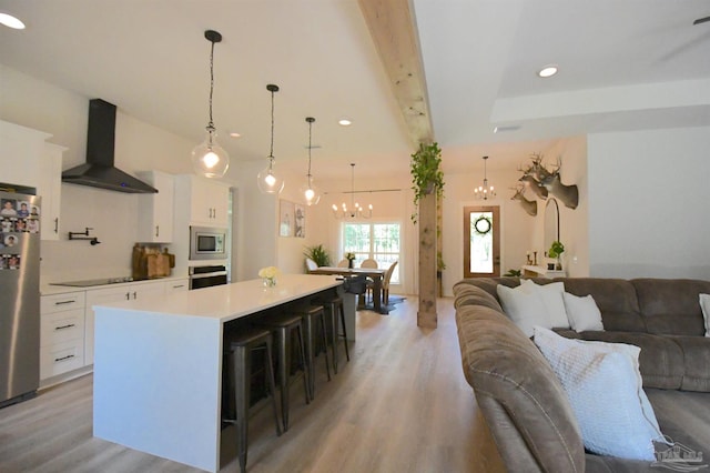 kitchen with white cabinets, appliances with stainless steel finishes, wall chimney exhaust hood, and a large island