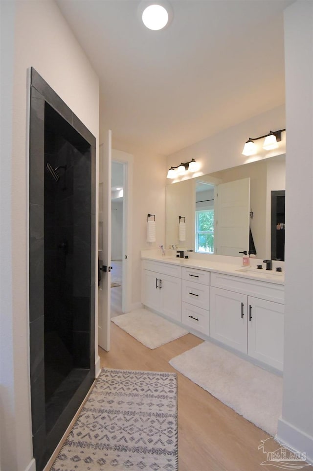 bathroom featuring dual vanity, walk in shower, and hardwood / wood-style flooring