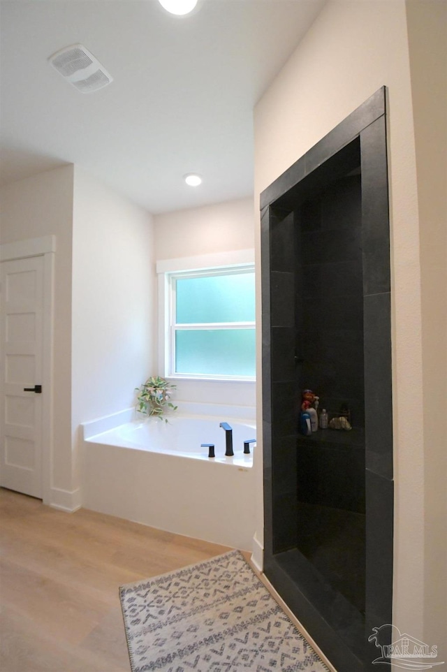 bathroom featuring plus walk in shower and hardwood / wood-style flooring