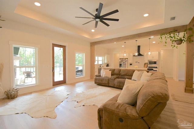 living room featuring ceiling fan and a tray ceiling