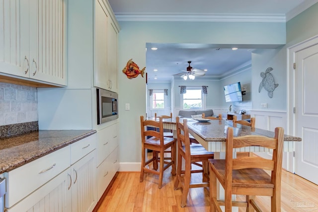 dining area with ceiling fan, light wood-type flooring, and crown molding