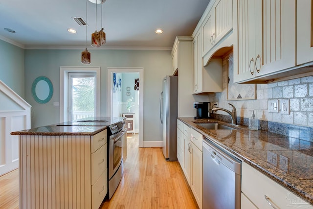 kitchen featuring light hardwood / wood-style floors, sink, hanging light fixtures, a kitchen island, and appliances with stainless steel finishes