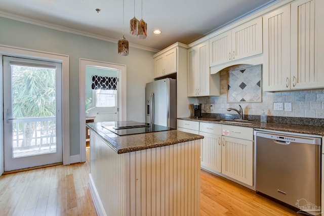 kitchen with pendant lighting, a center island, light hardwood / wood-style flooring, stainless steel appliances, and ornamental molding