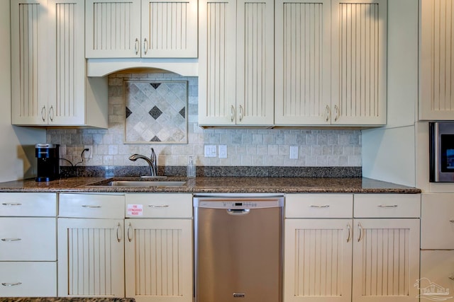 kitchen with dark stone counters, dishwasher, sink, white cabinetry, and decorative backsplash