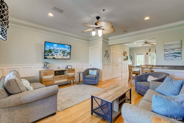 living room featuring ceiling fan, light wood-type flooring, and crown molding