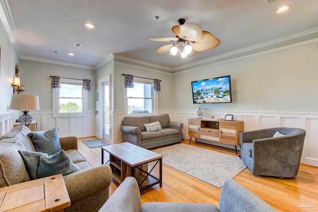 living room featuring wood-type flooring, crown molding, and ceiling fan