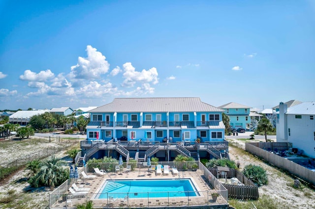 back of property with a balcony, a patio, and a community pool