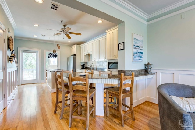 dining space with ornamental molding, sink, ceiling fan, and light hardwood / wood-style flooring