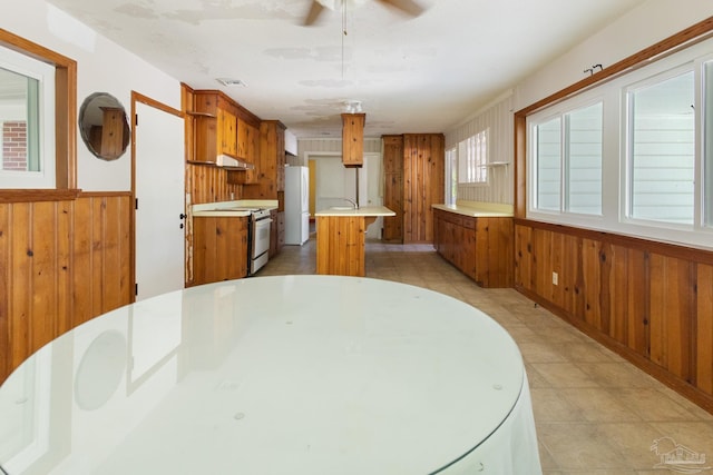 dining space with ceiling fan and wooden walls