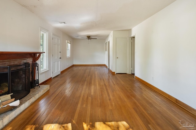 unfurnished living room with ceiling fan, hardwood / wood-style floors, and a brick fireplace