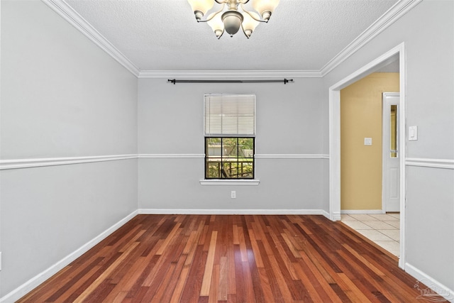 empty room with ornamental molding, wood-type flooring, a textured ceiling, and an inviting chandelier