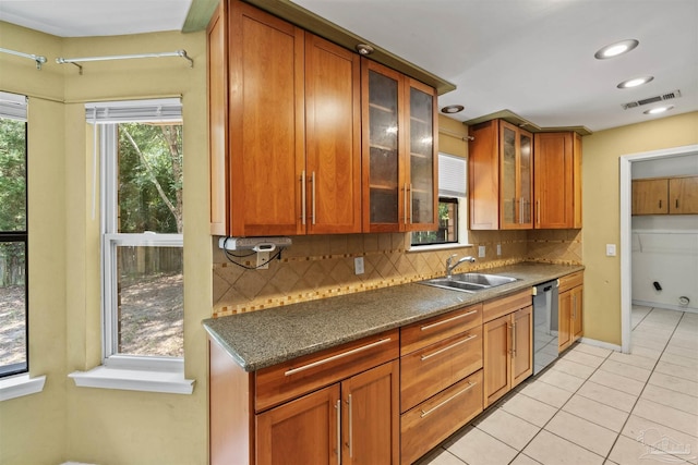 kitchen with stainless steel dishwasher, sink, decorative backsplash, and light tile patterned floors