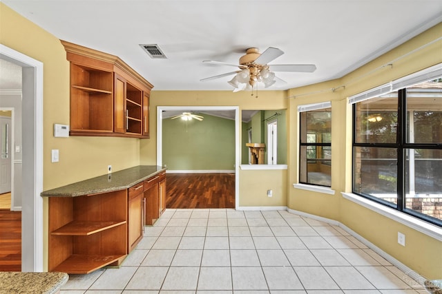 kitchen with dark stone countertops, plenty of natural light, light tile patterned floors, and ceiling fan