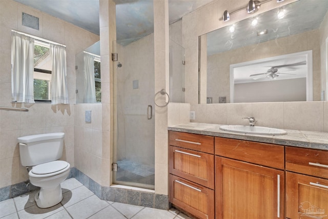 bathroom featuring tile patterned floors, toilet, tile walls, vanity, and a shower with door