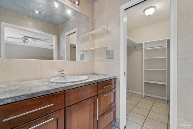 bathroom with tasteful backsplash, tile walls, vanity, ceiling fan, and tile patterned floors