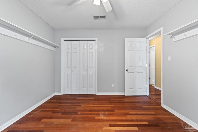 unfurnished bedroom featuring ceiling fan, a textured ceiling, dark hardwood / wood-style flooring, and a closet