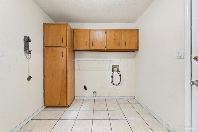 laundry area with gas dryer hookup, hookup for a washing machine, cabinets, a textured ceiling, and light tile patterned flooring