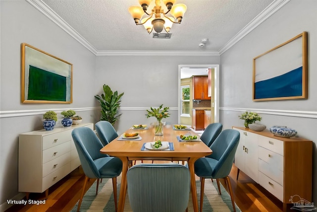 dining space featuring ornamental molding, a chandelier, hardwood / wood-style floors, and a textured ceiling