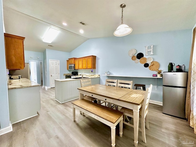 dining room with lofted ceiling and light hardwood / wood-style floors