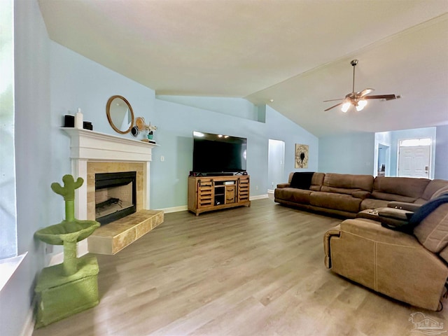 living room with ceiling fan, hardwood / wood-style flooring, a fireplace, and vaulted ceiling