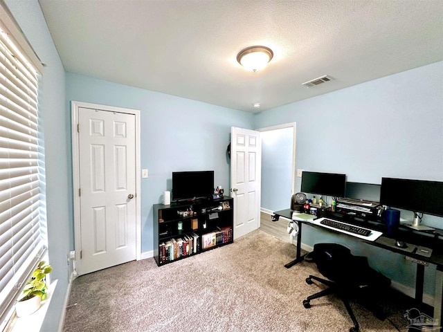 carpeted office featuring a textured ceiling