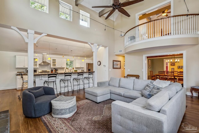 living room featuring a towering ceiling, ceiling fan, and dark wood-type flooring