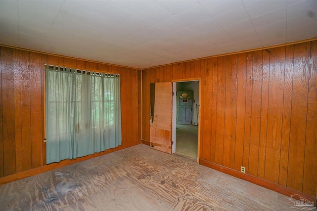 unfurnished room with baseboards and wooden walls