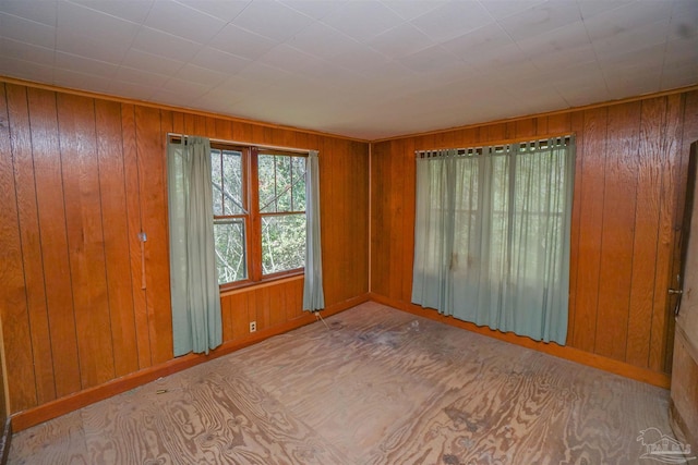 empty room featuring wooden walls and baseboards