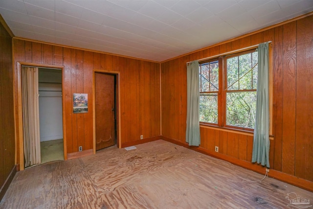 unfurnished bedroom featuring wood walls, two closets, and visible vents