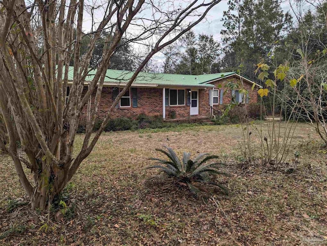 single story home with metal roof and brick siding