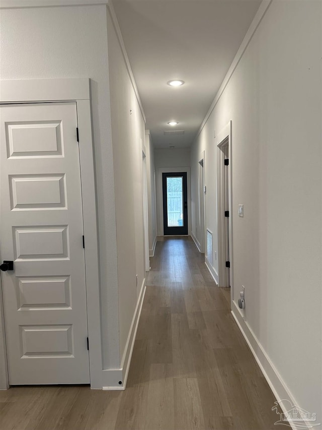 corridor featuring baseboards and wood finished floors