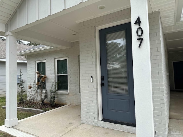 entrance to property featuring board and batten siding and brick siding