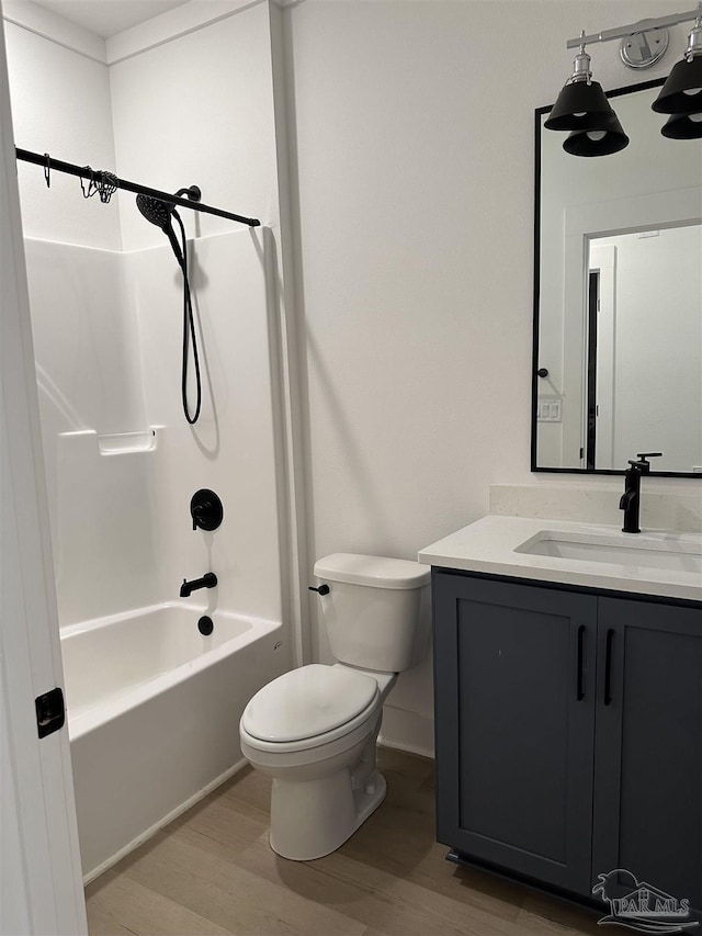 bathroom featuring toilet, vanity, shower / tub combination, and wood finished floors