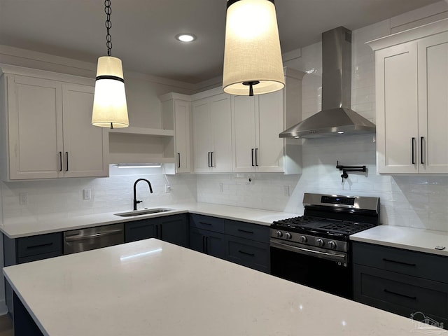 kitchen with stainless steel appliances, white cabinetry, a sink, and wall chimney exhaust hood