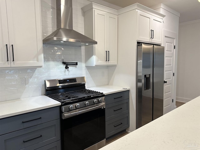 kitchen featuring tasteful backsplash, appliances with stainless steel finishes, light stone counters, wall chimney range hood, and white cabinetry