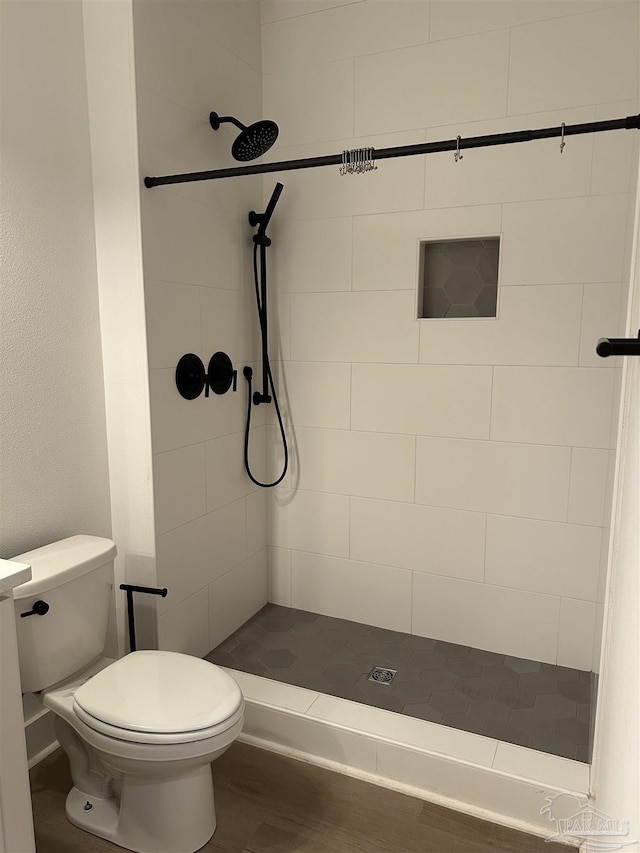 bathroom featuring a shower stall, toilet, and wood finished floors