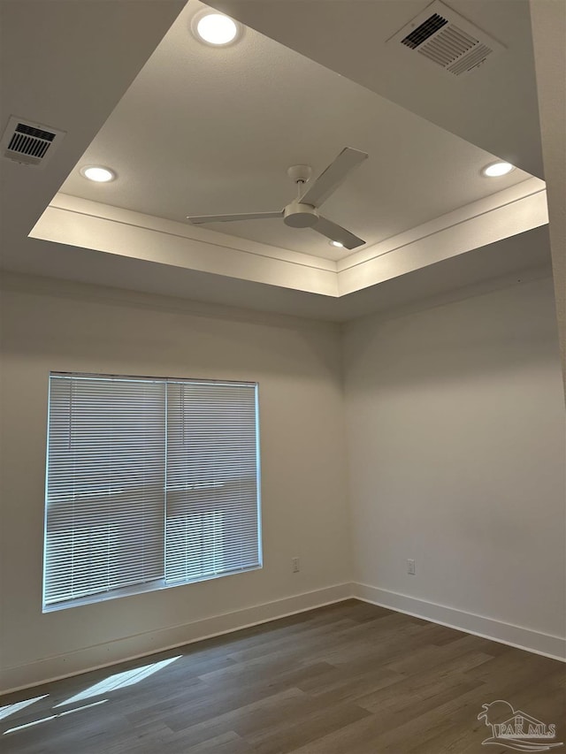 unfurnished room with visible vents, a tray ceiling, and a ceiling fan