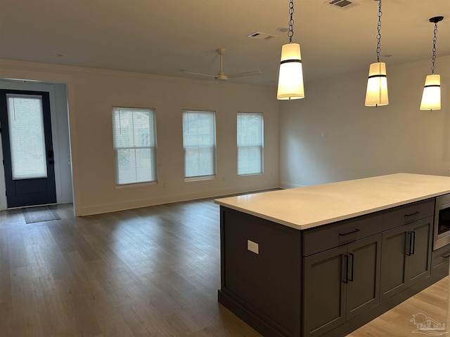 kitchen featuring wood finished floors, open floor plan, light countertops, and decorative light fixtures