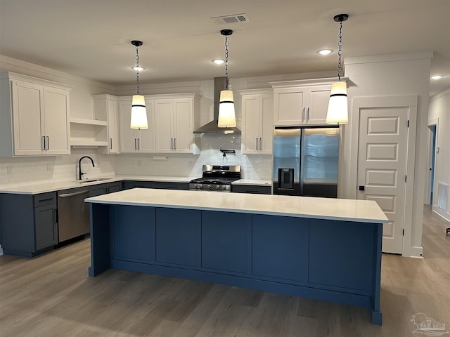 kitchen with wall chimney exhaust hood, appliances with stainless steel finishes, a center island, light countertops, and white cabinetry