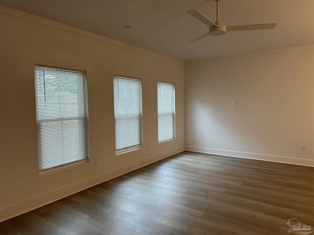 empty room with ornamental molding, ceiling fan, baseboards, and wood finished floors