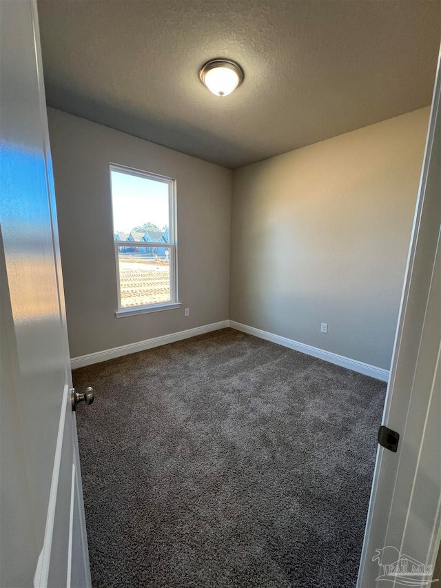 empty room with a textured ceiling and dark carpet