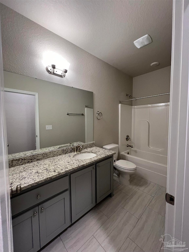 full bathroom featuring vanity, a textured ceiling, shower / washtub combination, and toilet