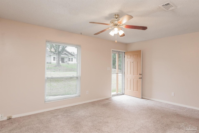 empty room featuring light carpet, ceiling fan, a textured ceiling, and baseboards