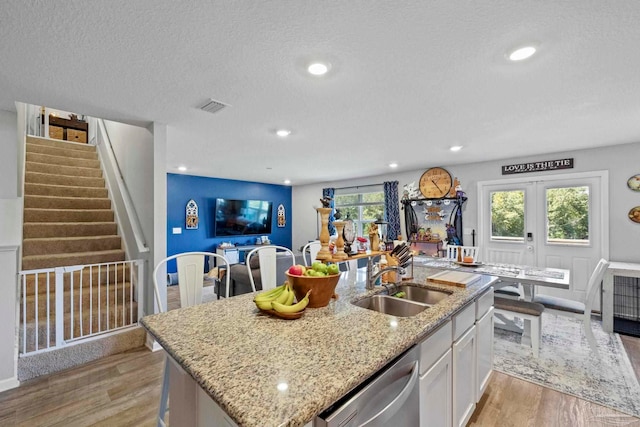 kitchen featuring white cabinetry, light wood-type flooring, plenty of natural light, and a kitchen island with sink