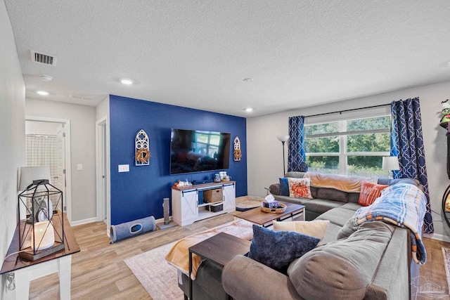 living room with a textured ceiling and light hardwood / wood-style floors