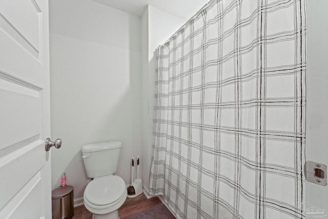 bathroom with toilet, wood-type flooring, and curtained shower