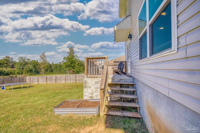 view of yard with a trampoline and a deck